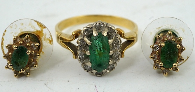 A yellow metal, emerald and diamond cluster set oval ring, size M and a pair of matching ear studs. Condition - poor to fair